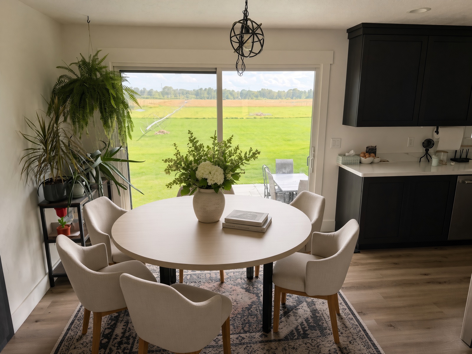 Round light wood-grain laminate dining table in a bright breakfast nook by a sliding door